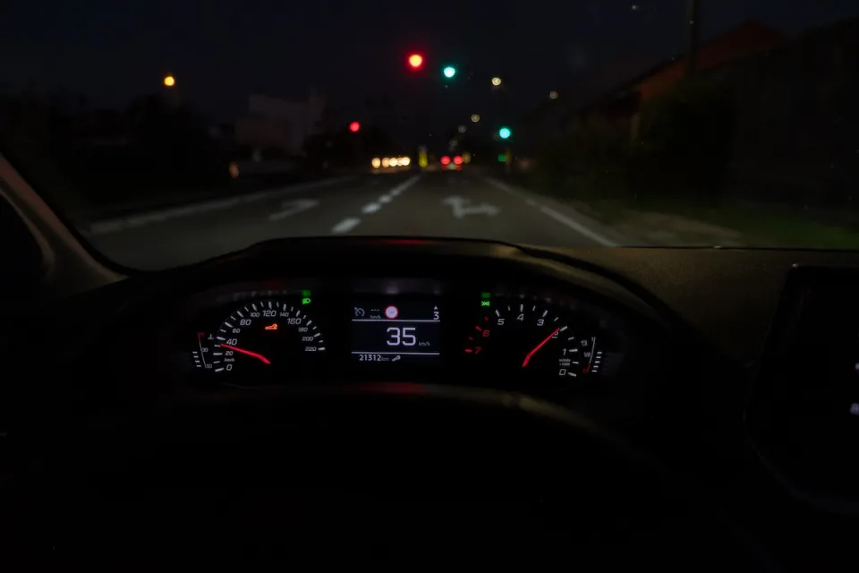 Close-up of car dashboard with speedometer at 35 on roadway at night.